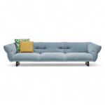 Stylish modern sofa with light blue upholstery and throw pillows