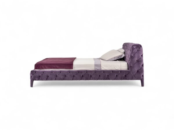 Luxury upholstered bed with plush violet velvet and elegant curves.