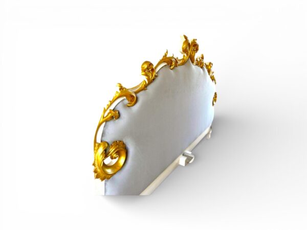 Elegant bed with luxurious gold leaf carvings and soft fabric upholstery