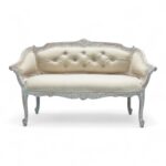 Classic carved loveseat with neutral fabric upholstery and tufted backrest