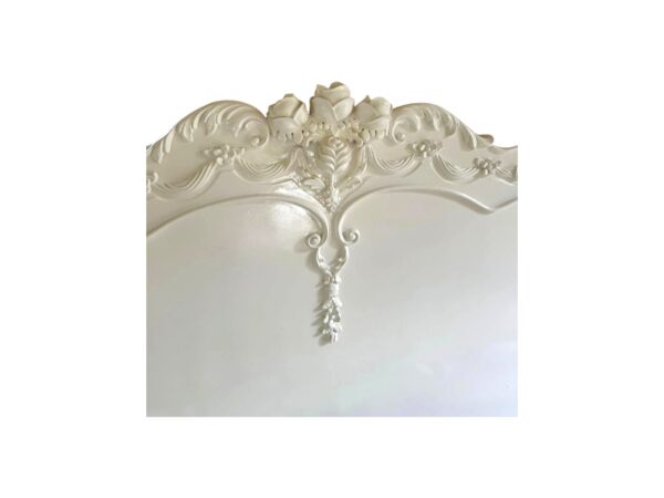 Antique-style French bed with soft white paint and carved detailing