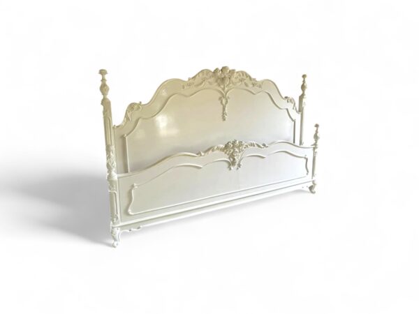 Antique-style French bed with soft white paint and carved detailing
